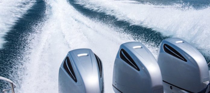 Three engines on a boat which create a large wake behind the boat sailing through a sea studded with a few islands.