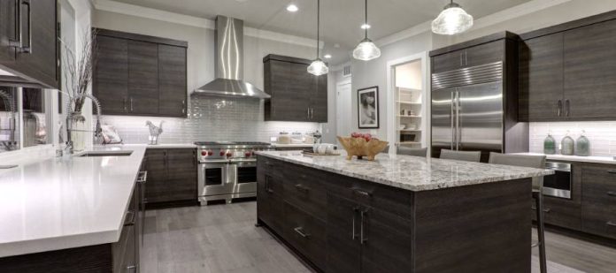 A modern kitchen with white and dark brown elements, along with stainless steel appliances and marble countertops.