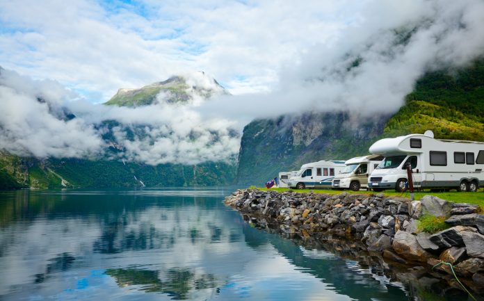 A stunning view of a Norwegian valley with a river running through it, with recreational vehicles parked at the bank.