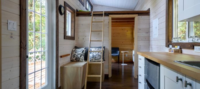 A close-up of a wooded and older interior design of a dining room and kitchen in a tiny rustic log cabin.