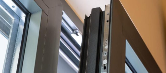 Close-up of the corner of an open aluminum window. It features a gray frame and a visible locking system.