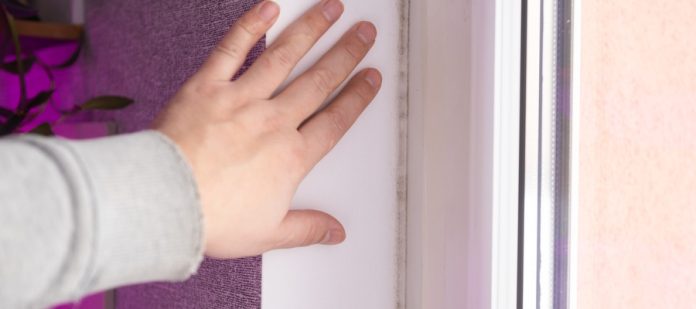 A person running their hand along the inner wall next to their window. The rest of the wall is a bright purple.