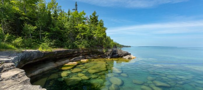 A stone ledge reaching over Lake Superior's Paradise Cove, with small boulders and stones visible in the water.