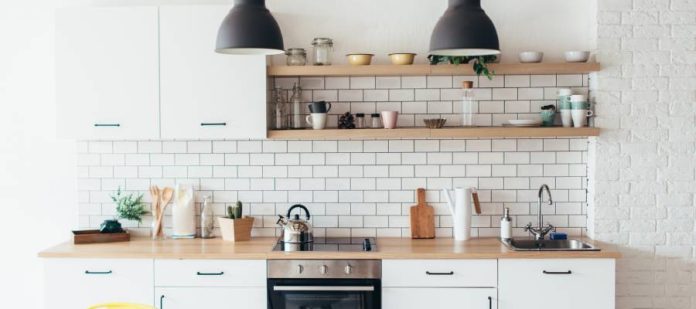 A brightly lit kitchen with white cabinets, open shelving, subway tile backsplash, and butcher block countertops.