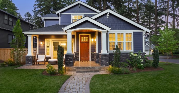 The exterior of a blue home in Ohio with white trim and columns around the porch. The door is stained wood.